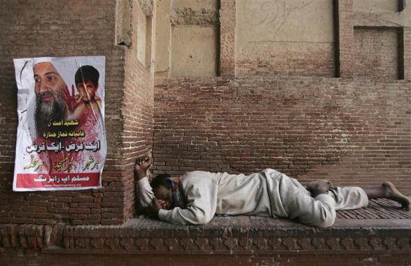 (A man takes a nap next to a poster of Osama bin Laden