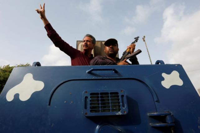 Waseem Akhtargestures from an armoured personal carrier while being taken to jail after his arrest